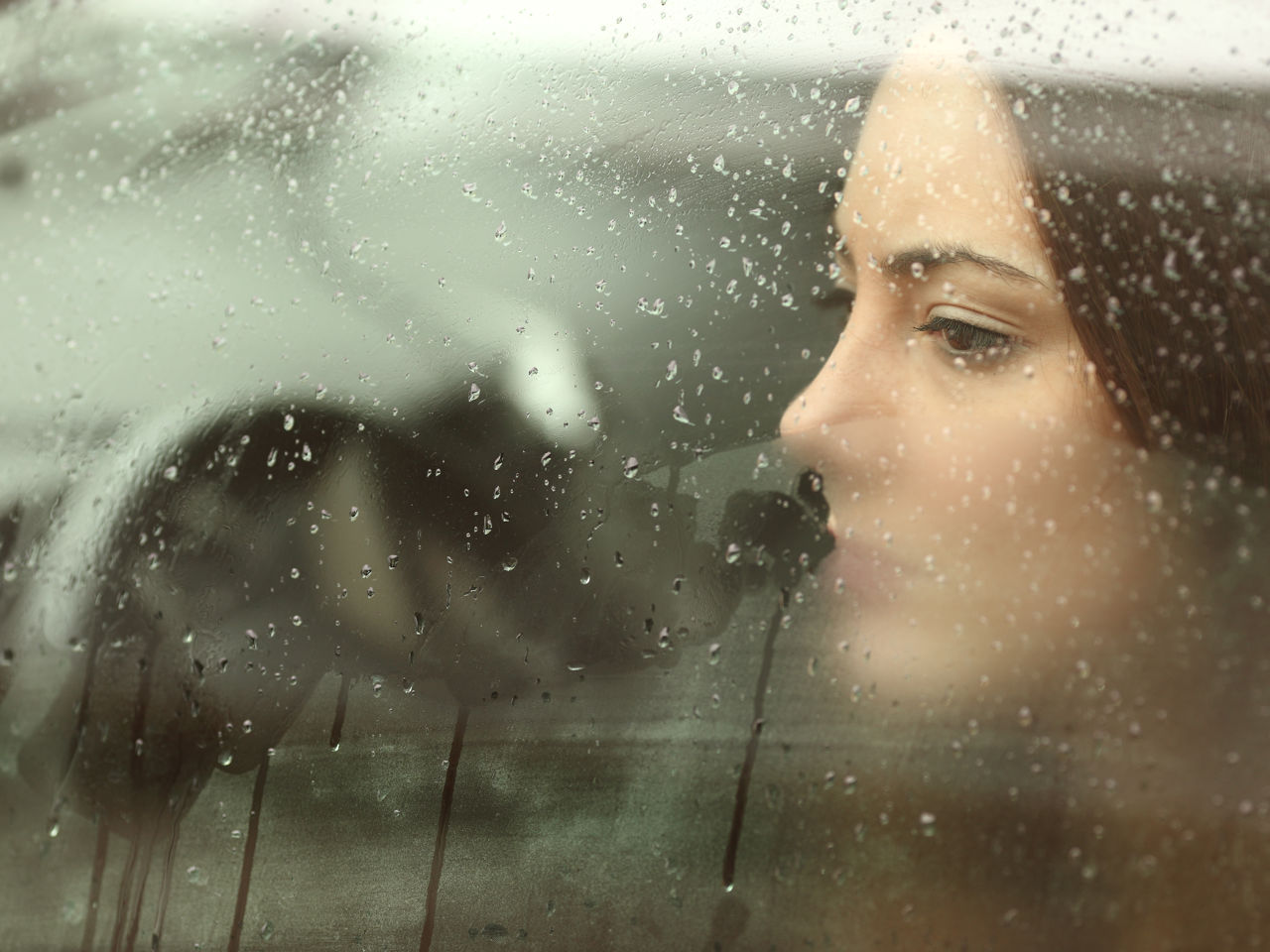 Kvinde kigger ud af dugget rude