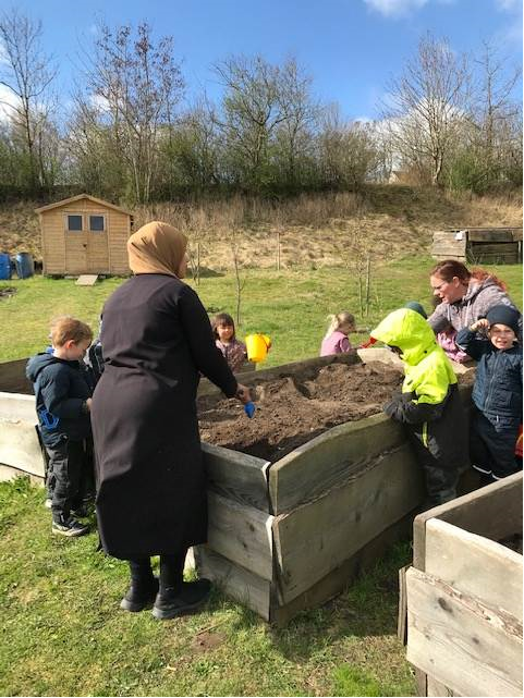 Kvinder og børn der planter i plantekasse