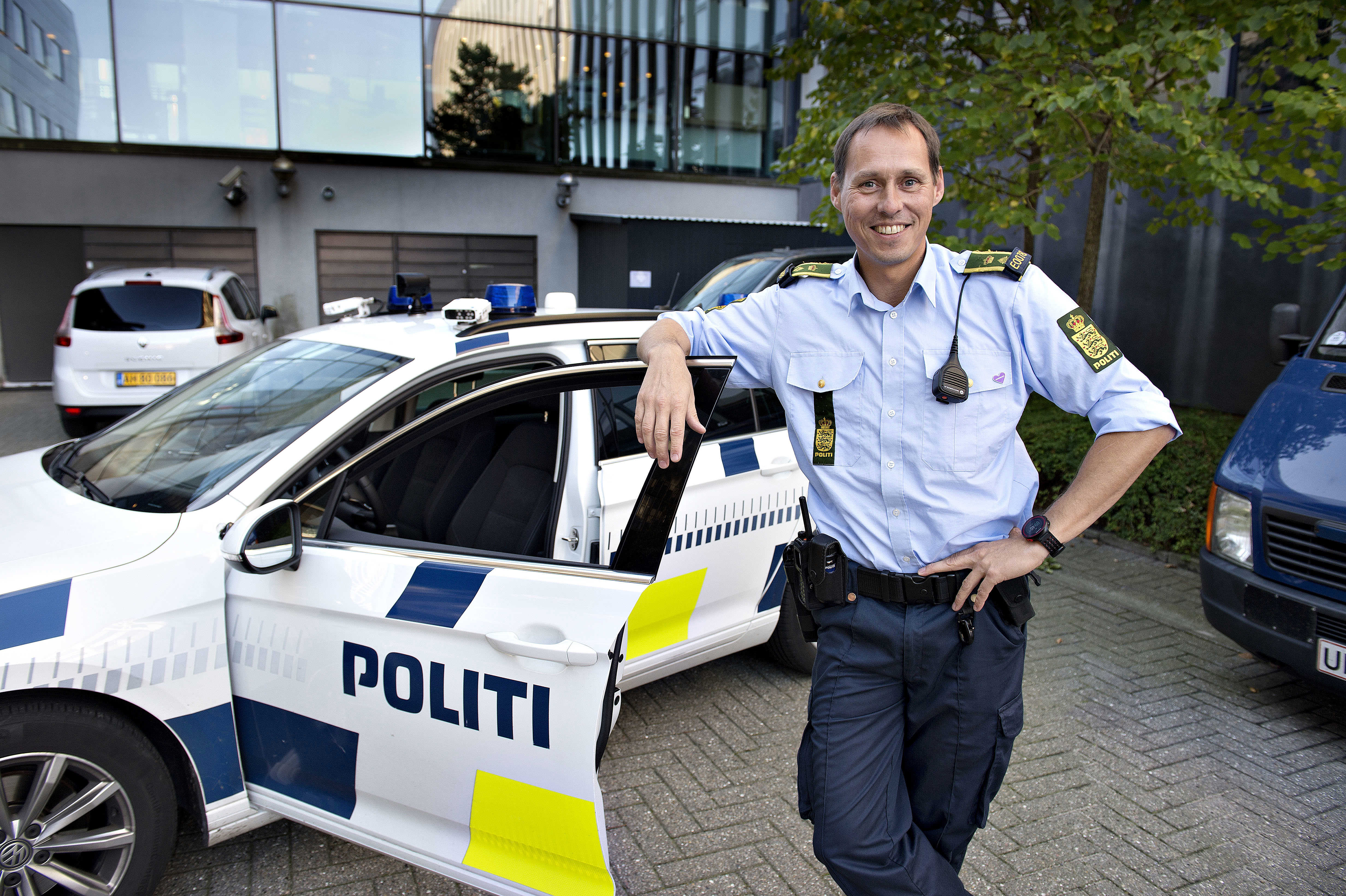 Politibetjent, der læner sig op af døren til politibil