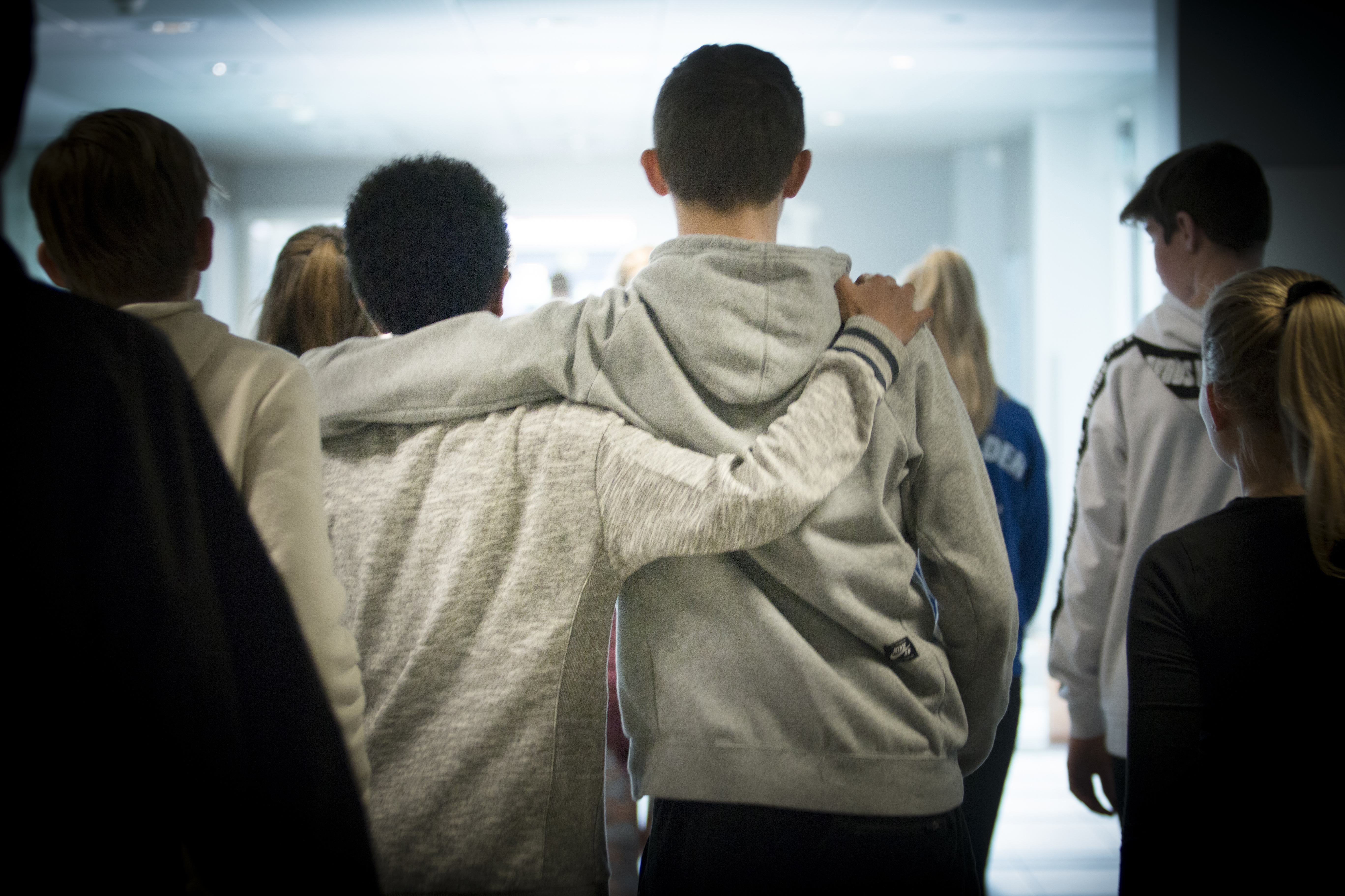 En Gruppe Unge Menensker, der holder om hinanden, fotograferet Bagfra