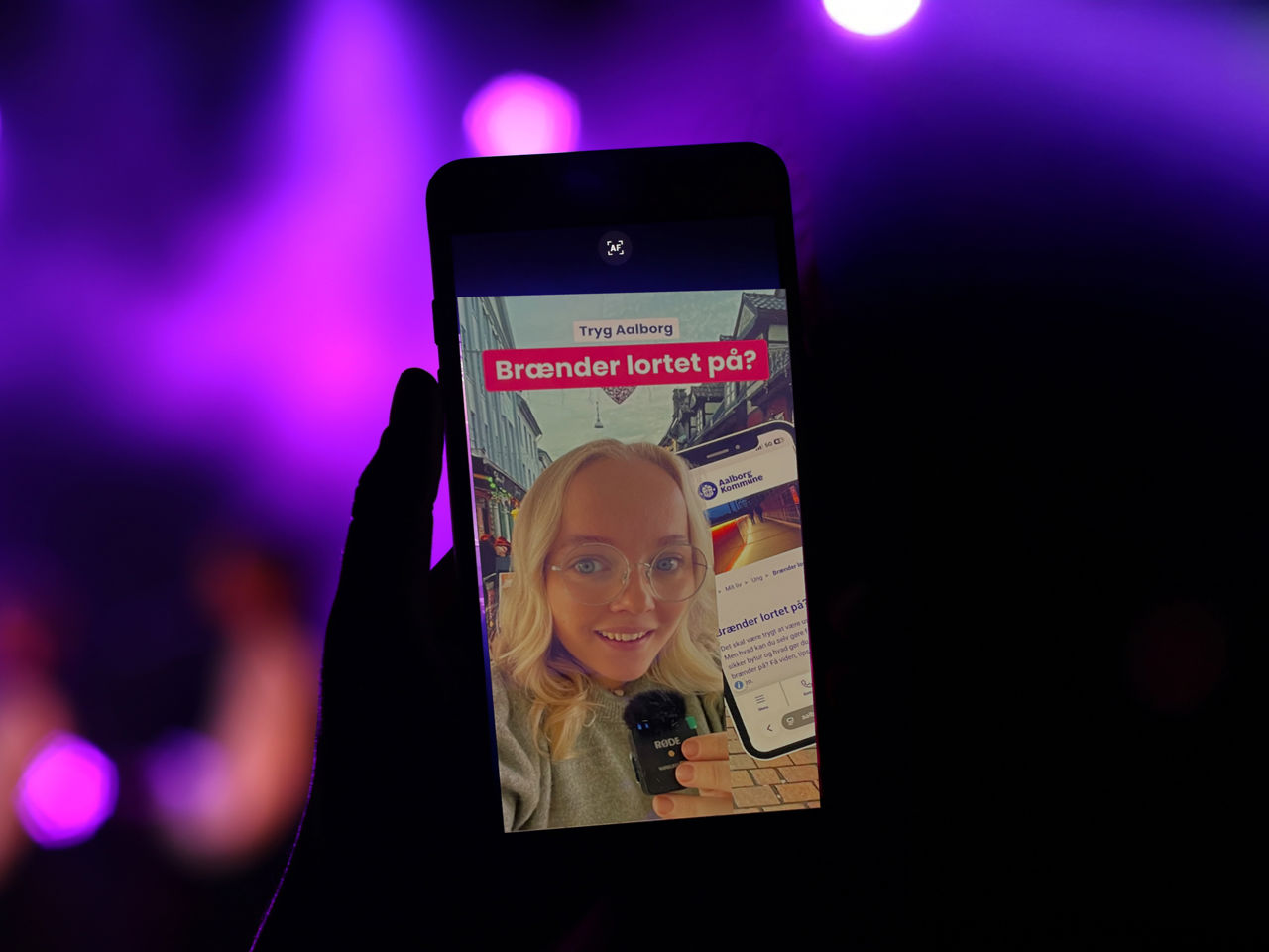To personer i nattelivet, der ser video på deres telefoner om Safezones og Nødinfo.