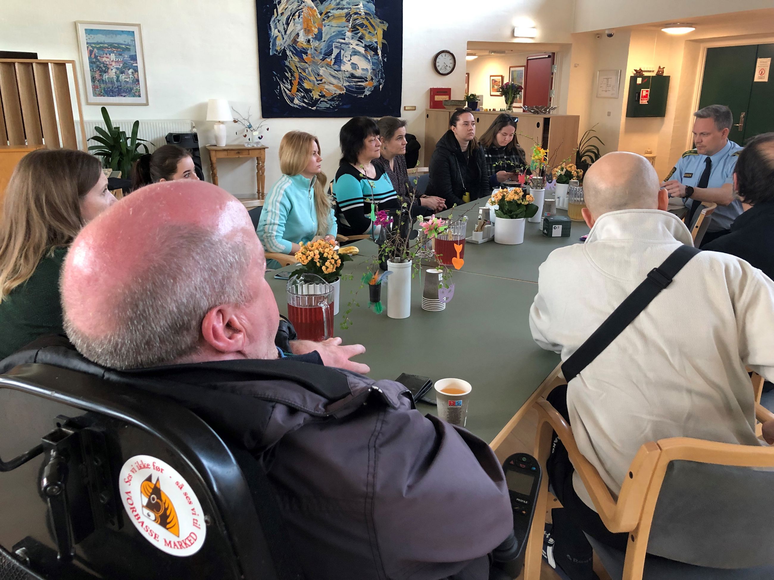 Mennesker der sidder omkring et bord og hører politibetjent fortælle om tryg digital kommune