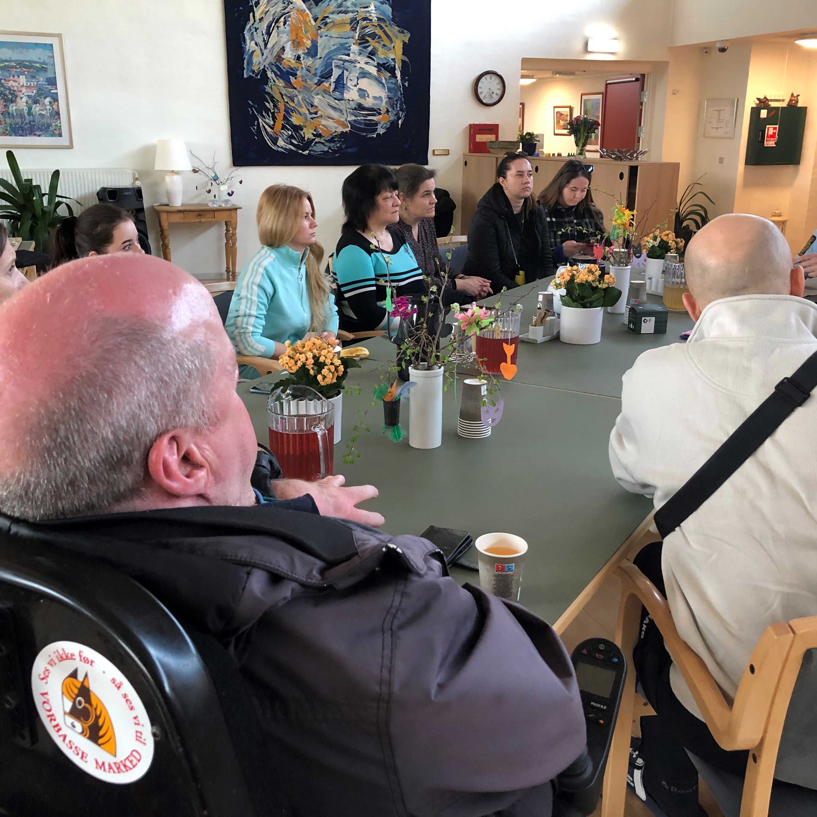 Mennesker der sidder omkring et bord og hører politibetjent fortælle om tryg digital kommune