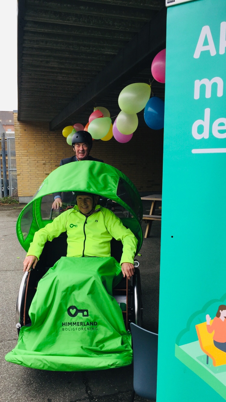 En mand, der sidder i en rigshaw og en anden mand, der cykler.