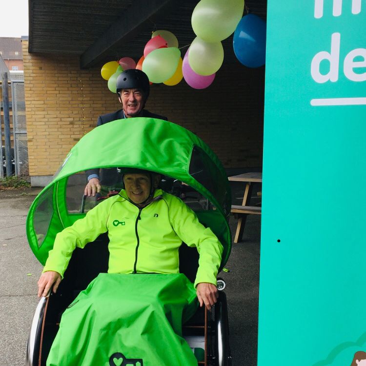 En mand, der sidder i en rigshaw og en anden mand, der cykler.