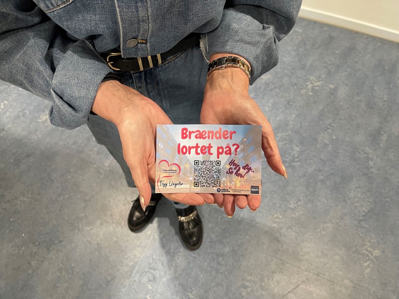 Uddeling af postkort med Brænder lortet på logo samt QR kode til hjemmesiden. Logoer fra Tryg Aalborg, Nordjyllands Politi og Aalborg Kommune.