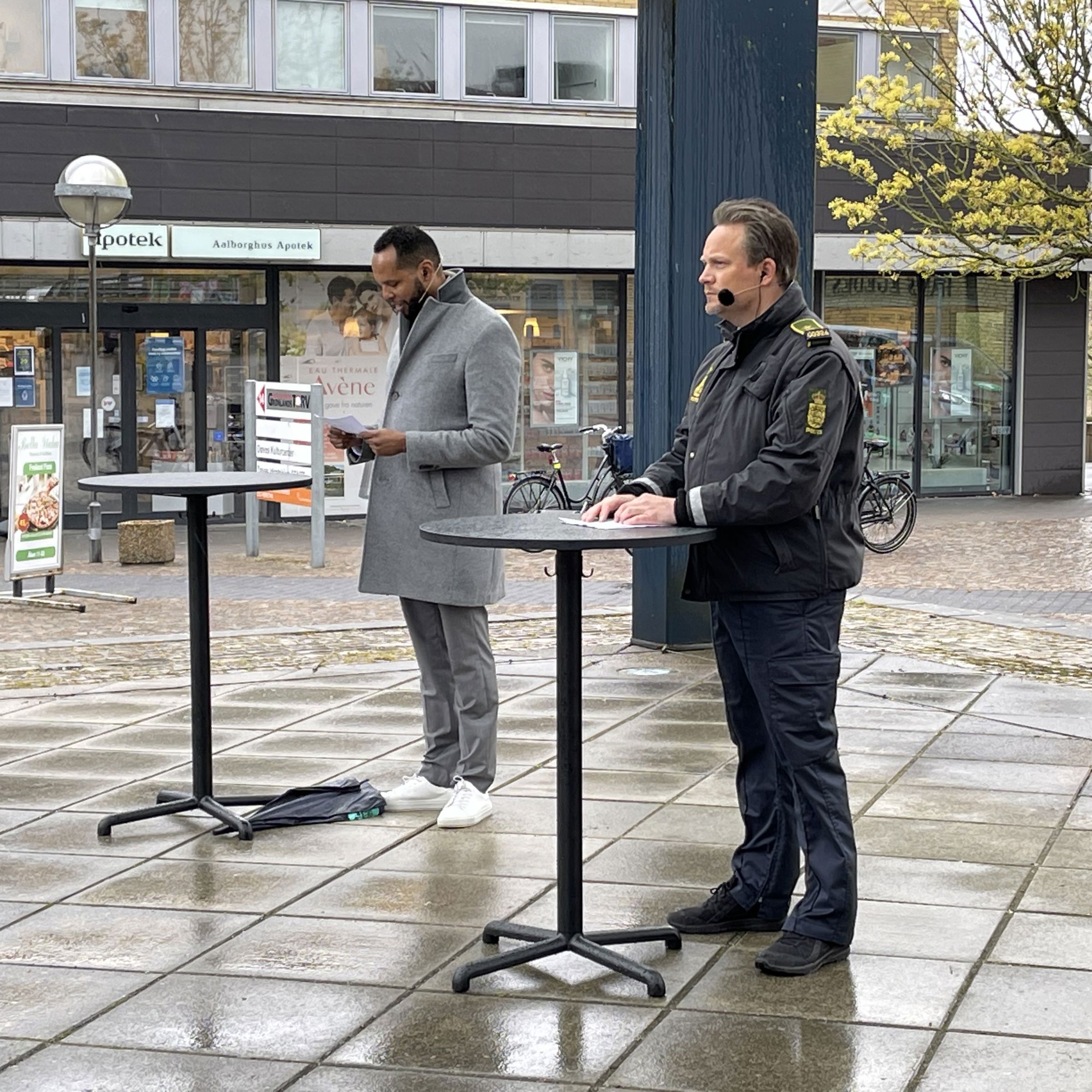 En politibetjent og en mand, der står ved borde, opstillet på gaden