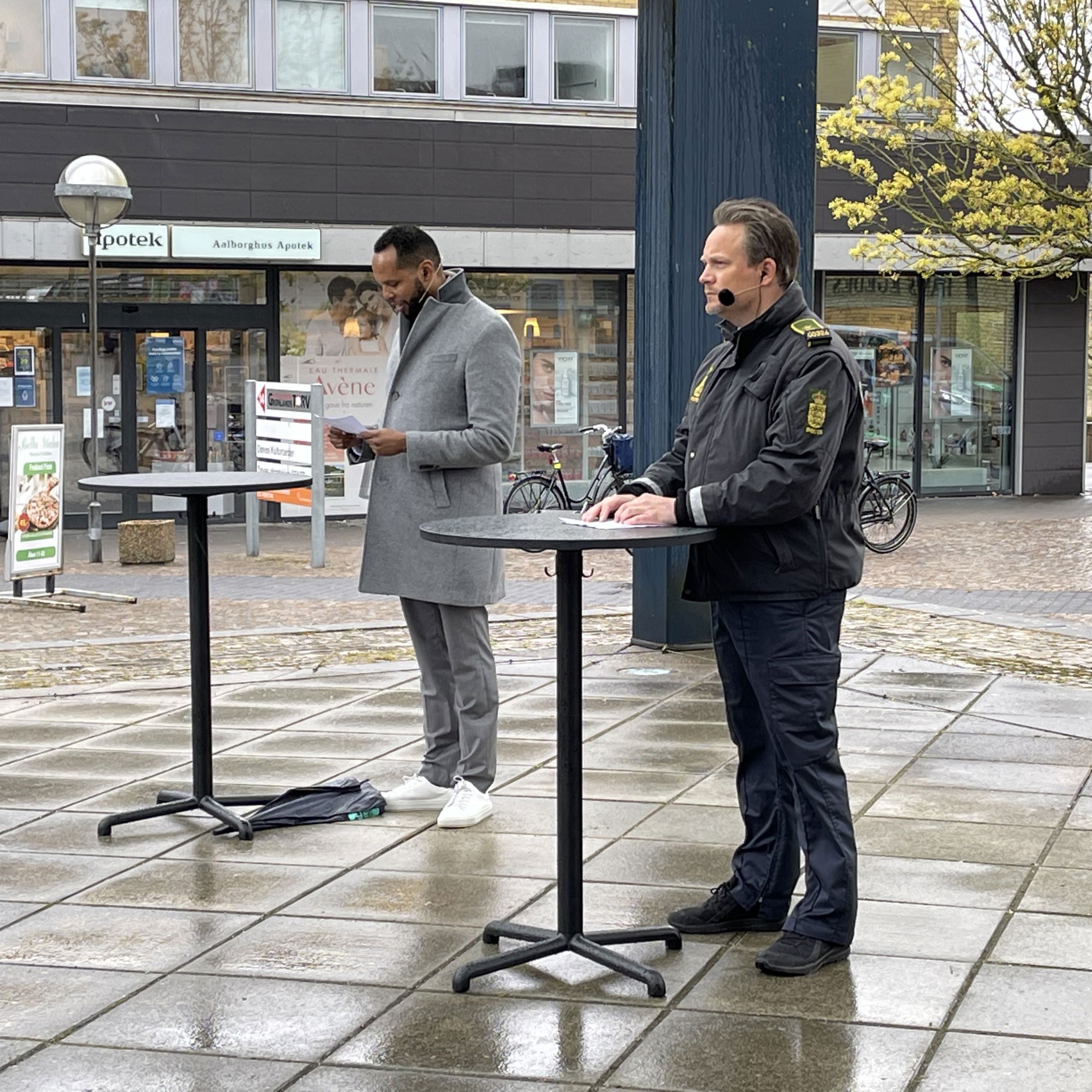 En politibetjent og en mand, der står ved borde, opstillet på gaden